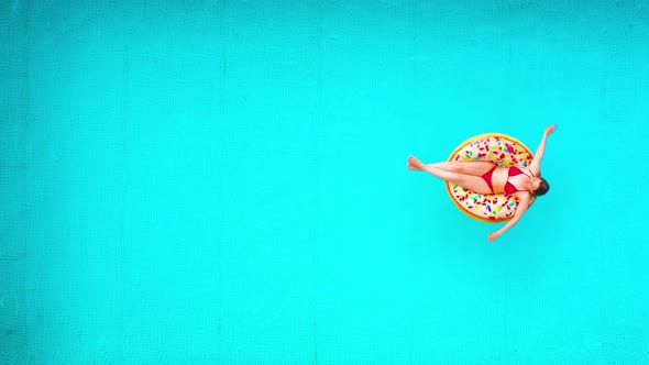 Aerial View of a Woman in Red Bikini Lying on a Donut in the Pool
