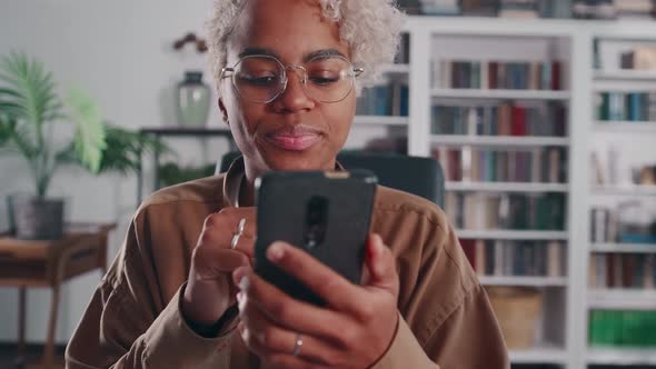 Young African American Woman Holding Phone and Moving Finger Across Screen