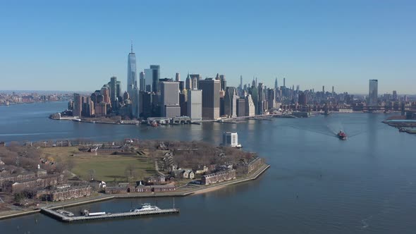 An aerial view of New York harbor on a sunny day with blue skies. The camera truck right, boom up an