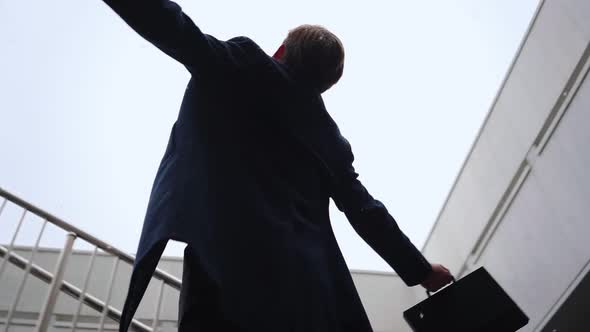 Successful Businessman with Raised Hands Celebrating His Victory During Snowfall