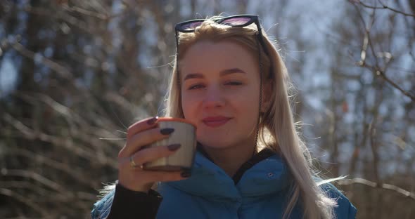 girl with sunglasses on her hair drinks a hot mug of tea coffee steam comes out