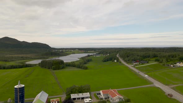 Aerial flight over agriculture farm with green grass field and Fjord in background - Norway,Europe