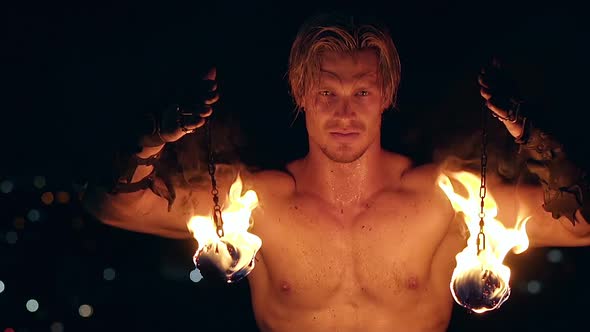 Young Blond Male Holds Two Pois Hanging on Chains. Male Stares at Camera. Slow Motion Shot. Close-up