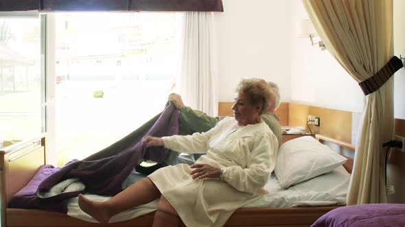 Two Elderly People Going To Bed in Hospital Rehab Clinic