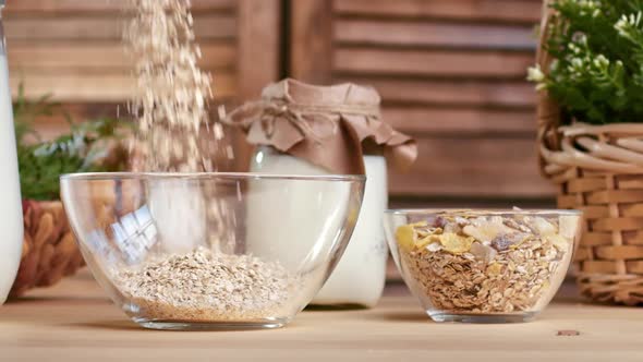 Sprinkling Fresh Cereal Muesli Glass Bowl Preparing Healthy Breakfast with Farm Milk on Wooden Table