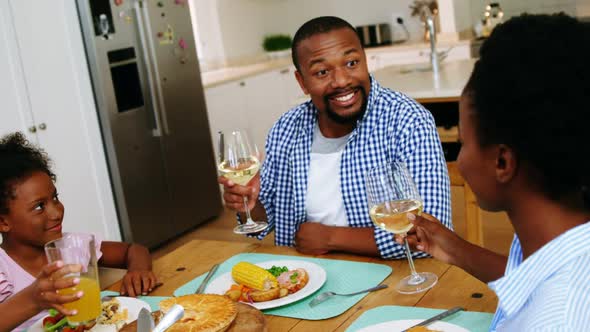 Happy parents and daughter toasting a glasses of drink