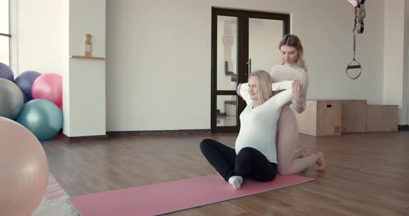 Happy Trainer Helping Pregnant Woman Doing Stretching Exercises