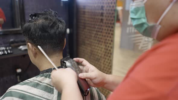 A Back Side View of a Professional Hairdresser Cutting a Man's Hair in Beauty Saloon