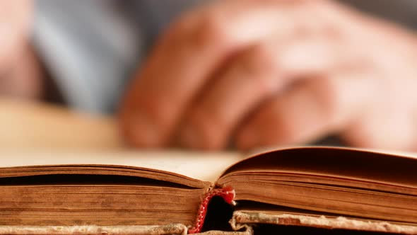 The concept of the study of old books.Close-up male hands in defocus flipping through the pages of a