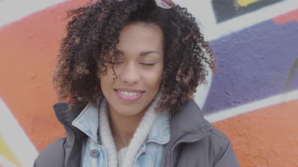 Beautiful Smiling Young Womant with Afro Haircut Posing Outdoor with Graffiti