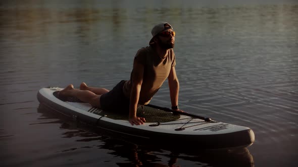 Man Meditating Pose Sup Board On Vacation. Stretching Exercise Stress Leisure Surfing Boat Fitness.