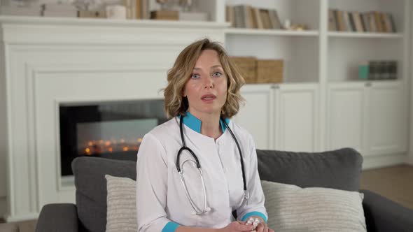 Happy Female Doctor Waving Hello to Patient During Home Care Visit