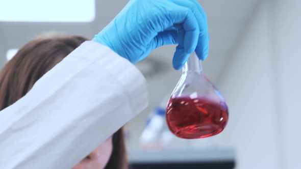 Lab Worker Shakes Flask with Liquid for Scientific Research