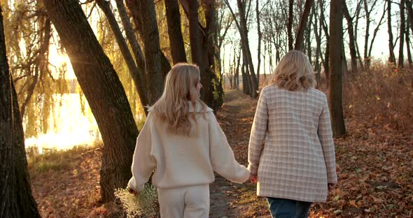 Rare View Pregnant Mother with Blonde Adult Daughter in Beige Clothes in Autumn Evening Park