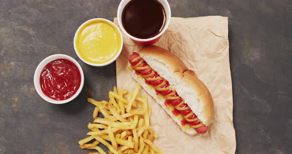 Video of hot dog with mustard, ketchup and chips on a black surface