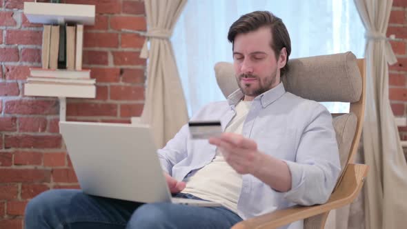 Casual Young Man Making Online Payment on Laptop on Sofa