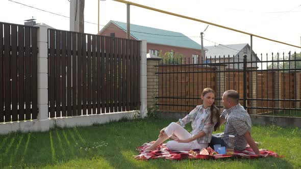 Woman and Handsome Man Sit in Yard and Son Jumps on Mother