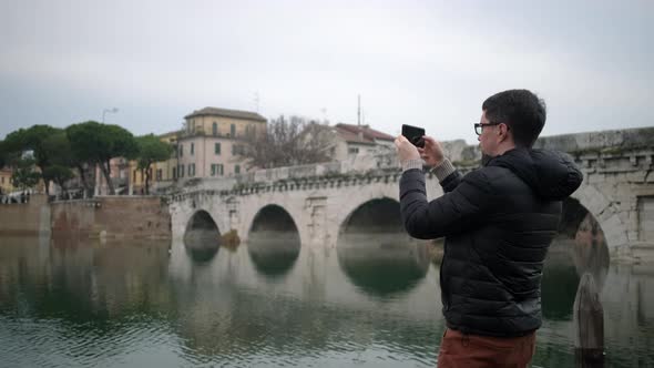 Guy Tourist Films Old Bridge Reflecting in River