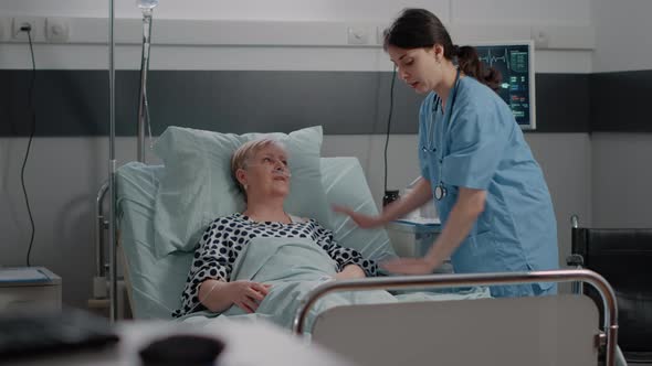 Doctor Doing Consultation with Senior Patient in Hospital Ward