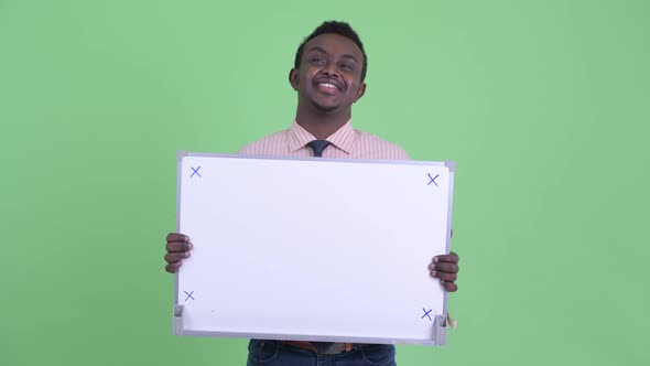 Happy Young African Businessman Thinking While Holding White Board