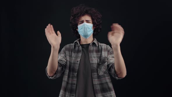 The Young Man with Curly Hair Wears a Mask Frowns Denies with His Hands Shows the Sign of Dislike