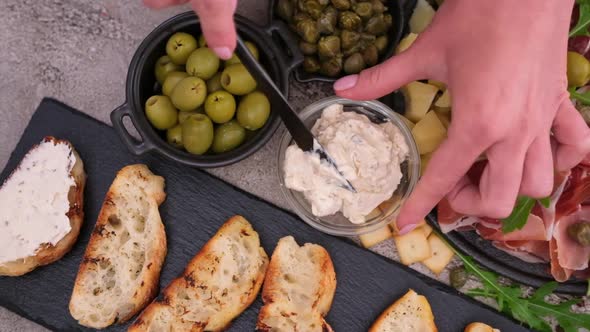 Making Bruschetta  Woman Smearing Cream Cheese on a Grilled Baguette