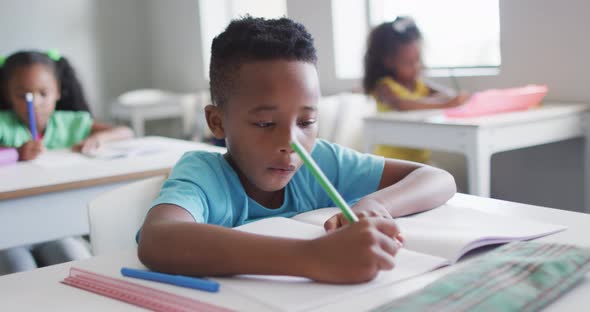 Video of focused african american boy doing lessons in classroom