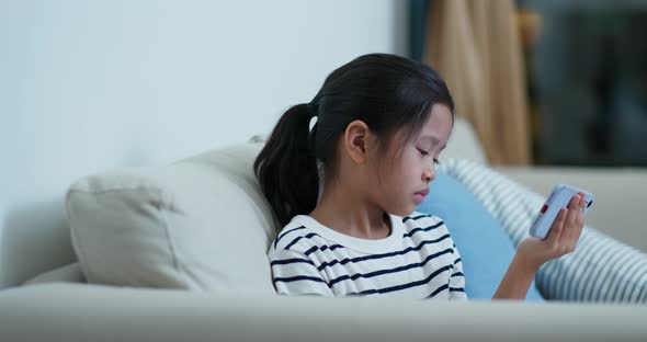 Young girl watch on the cellphone and sit on the sofa