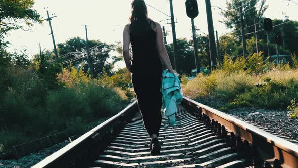 Young Beautiful Woman Walks Alone on the Railway Track