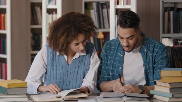 Students Guy and Girl Sitting in Library Doing Homework Preparing for Exam Talking Discussing