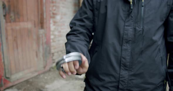 the Policeman Pulls Out the Handcuffs and Holds Them in Front of Him Close Up.