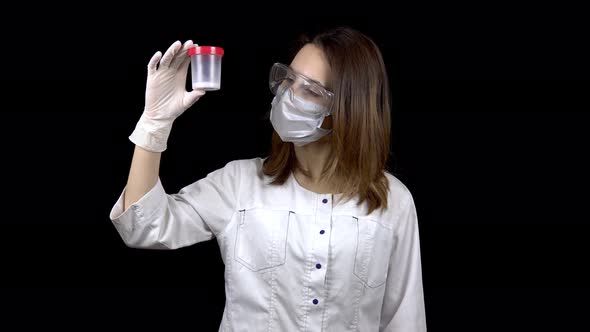 Young Woman Doctor Checks Sperm Tests. A Woman Examines a Test Jar, Then Shows a Thumb Up. Positive