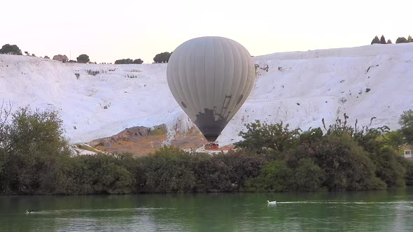 Hot Air Balloons in White Travertines and Lake of Pamukkale, a Touristic Natural World Heritage Site