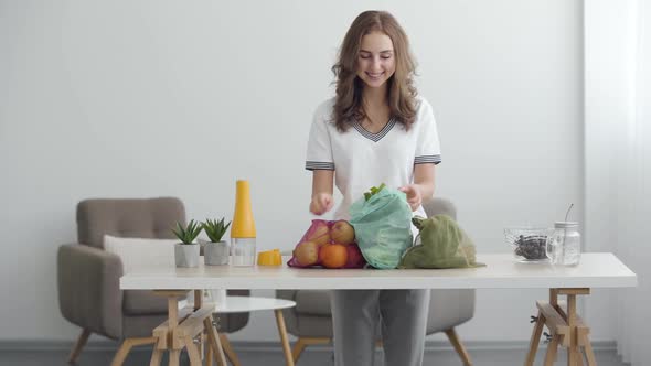 Young Cute Girl Preparing To Cooking a Salad. Vegetables and Fruits on the Table in a Cozy Kitchen