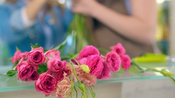 Small Pink Roses Stalks Lie on Shop Transparent Glass Table