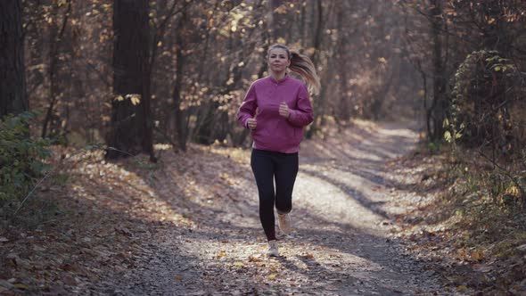 Caucasian Woman Runs Through the Autumn Forest with Yellow Leaves on the Trees