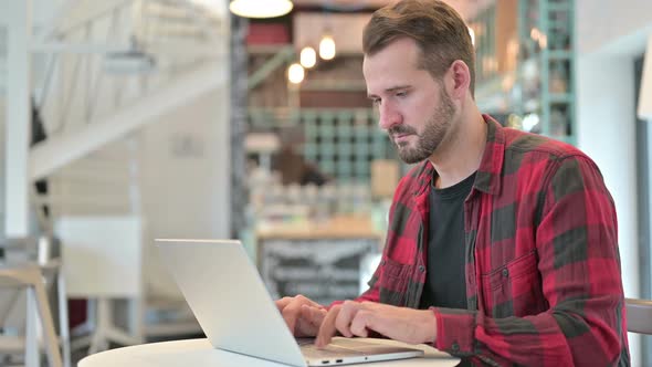 No Finger Sign By Young Man with Laptop in Cafe 