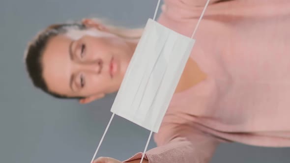 Young Woman Holds Face Mask in Front of Body Looking Ahead