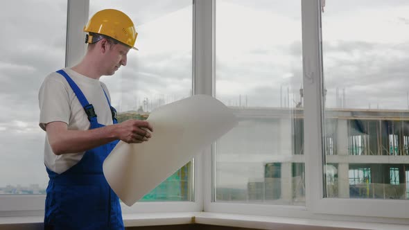 Builder at Construction Site with Blueprint