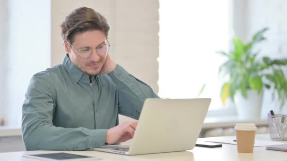 Middle Aged Man with Laptop having Neck Pain