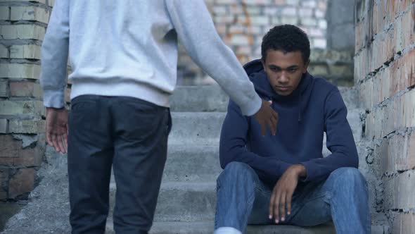 Young Man Stretching Out Hand to Sad Friends Sitting Stairs, Friendship Support