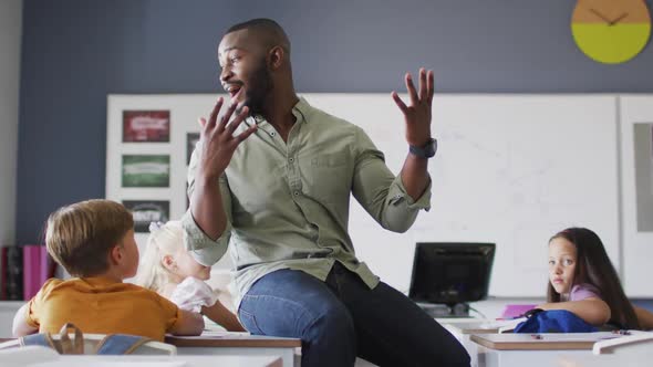 Video of happy african american male teacher during lesson with class of diverse pupils