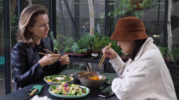 Two Girlfriends Having Conversation Over Their Healthy Vegan Lunch in Oriental Style . Enjoying