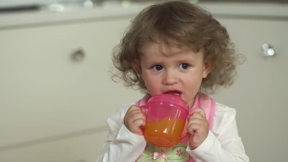 Baby Nutrition. Kid Drinking Juice From Baby Cup