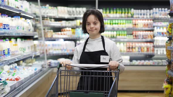 Store Employee with Down Syndrome Pushing Shopping Cart in a Local Supermarket