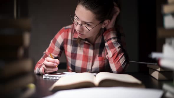 girl in the light of a night lamp is engaged in training. Student in preparation