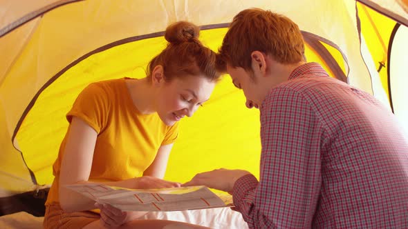 Happy Couple Sits Inside the Tent and Examines the Map
