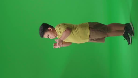 Side View Of Asian Little Boy Clapping His Hands In The Green Screen Studio