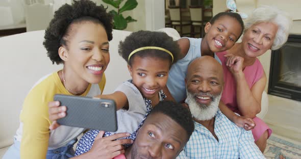 Happy african american family sitting and using smartphone in living room