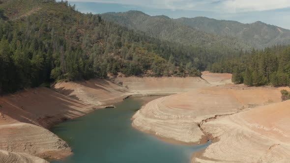 Aerial view of Shasta Lake flying by the water with hills in the background  Northern California low